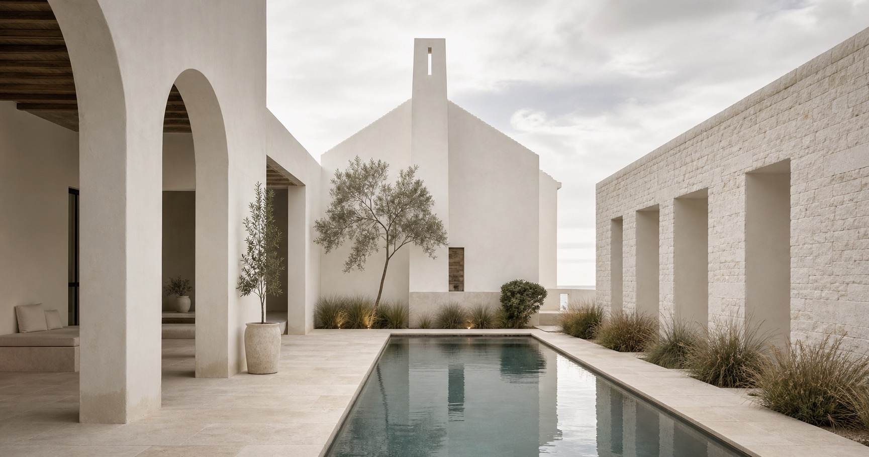 White stucco coastal courtyard with a narrow pool, pale stone, and calm architectural lines.